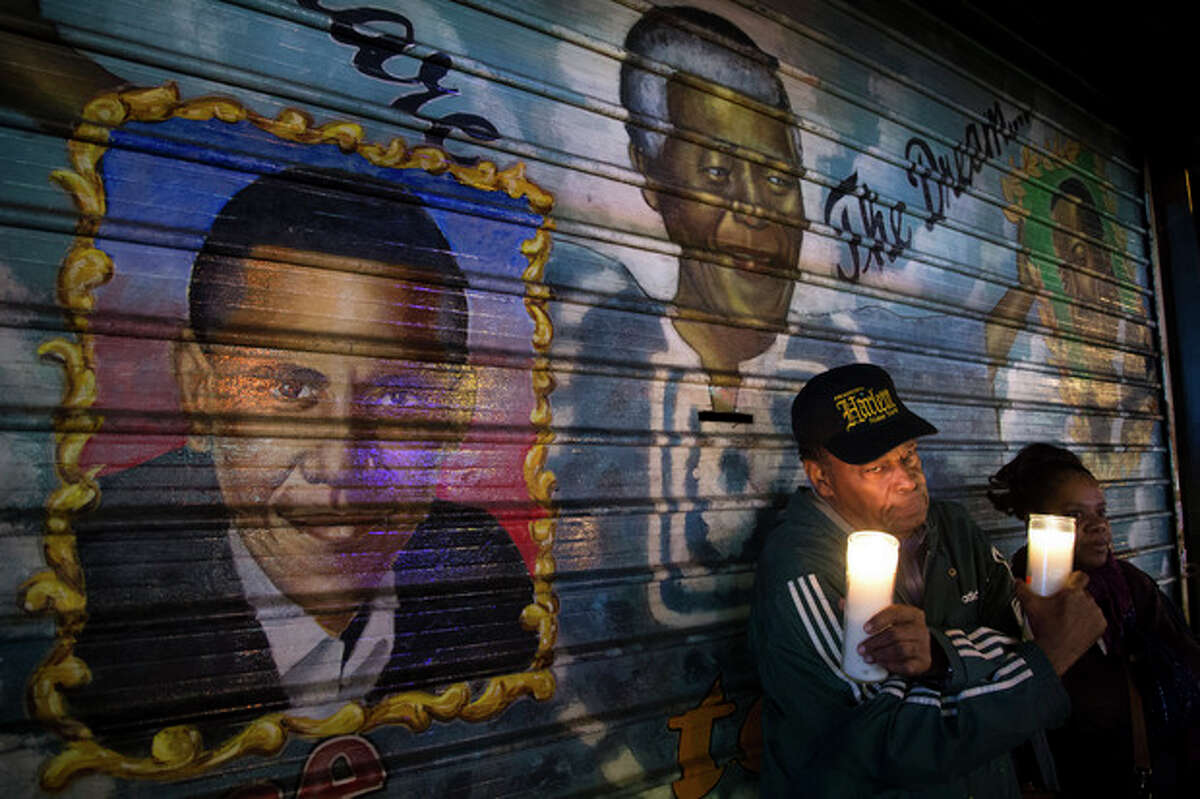 An artist who goes by the name "Franco the Great" stands in front of a mural of South African leader Nelson Mandela that he painted in 1995, and later added U.S. President Barack Obama, on 125th Street in the Harlem neighborhood of New York, Thursday, Dec. 5, 2013. Mandela, South Africa's first black president, died Thursday after a long illness. He was 95. (AP Photo/John Minchillo)