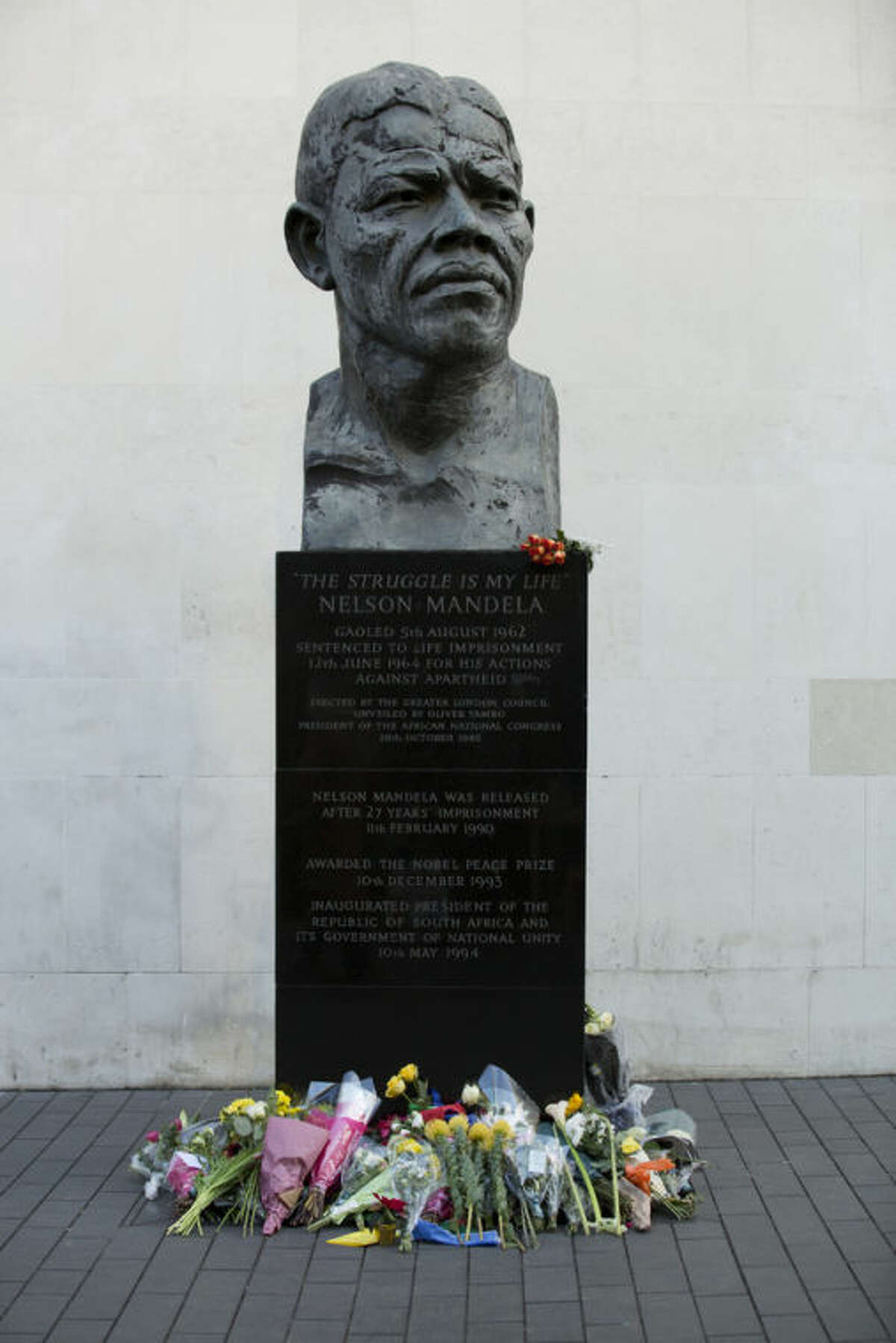Flowers are seen underneath a statue of former South African president Nelson Mandela, at the side of the Royal Festival Hall on the south bank of London, Friday, Dec. 6, 2013. Mandela passed away Thursday night after a long illness. He was 95. As word of Mandela's death spread, current and former presidents, athletes and entertainers, and people around the world spoke about the life and legacy of the former South African leader. (AP Photo/Jon Super)
