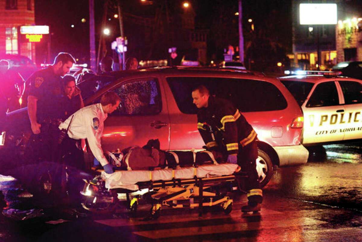 Hour photo / Erik Trautmann A woman is loaded onto a gurney after being hit by a motor vehicle at the intersection of West Cedar Street and Connecticut Avenue Friday night.
