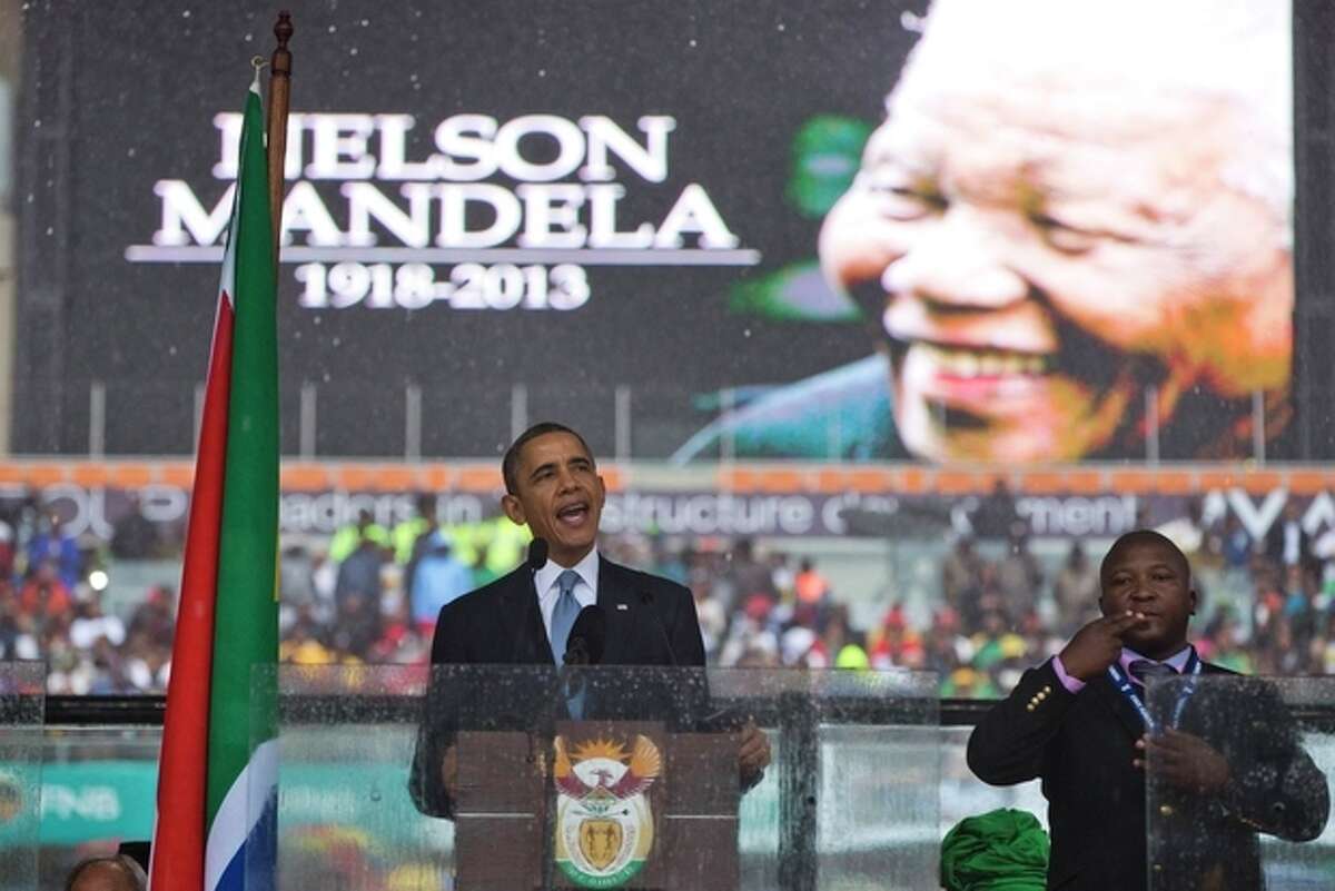 President Barack Obama delivers his speech next to a sign language interpreter during a memorial service at FNB Stadium in honor of Nelson Mandela on Tuesday, Dec. 10, 2013 in Soweto, near Johannesburg. The national director of the Deaf Federation of South Africa says a man who provided sign language interpretation on stage for Nelson Mandela?’s memorial service in a soccer stadium was a ?“fake.?”(AP Photo/ Evan Vucci)