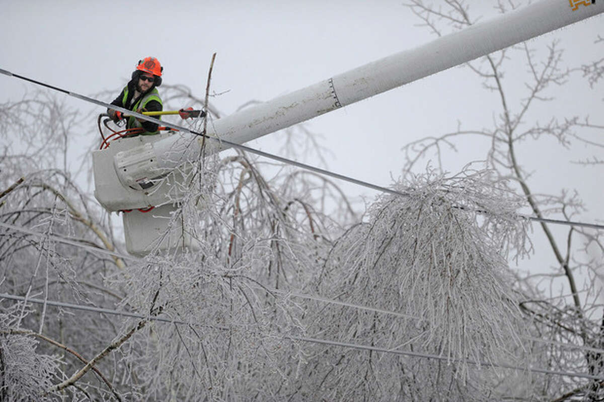 Andrew Powers, an arborist with Asplundh Tree Experts, clears iced branches from power lines along Mayflower Heights Drive in Waterville, Maine, on Monday, Dec. 23, 2013. Central Maine Power said nearly 57,000 were without power Monday afternoon, up from 29,000 it had been reporting earlier. Hardest hit was Kennebec County with about 20,000 and Waldo County at nearly 15,000 customers without power. (AP Photo/Morning Sentinel, Michael G. Seamans)