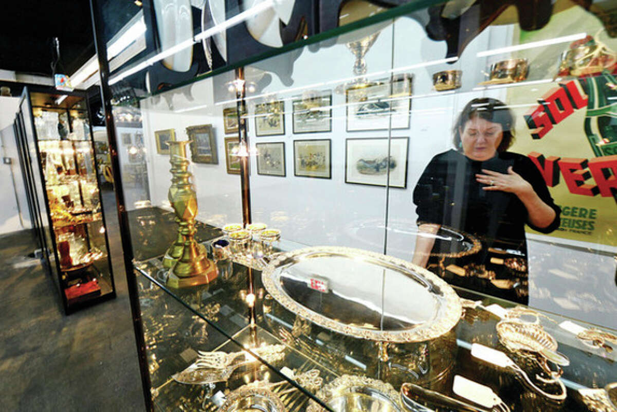 Hour photo / Erik Trautmann Barbara March, Sales and Marketing Manager at the new Antique and Design Center on Willard Ave. looks over some of the antique silver in the facilty that opened Dec. 15 with over 100 vendors.