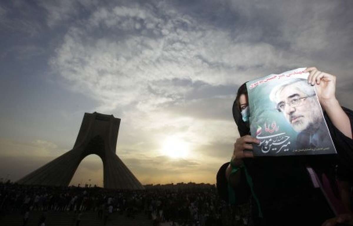 A female demonstrator holds up a poster of leading opposition presidential candidate Mir Hossein Mousavi, who claims there was voting fraud in Friday''s election, as she and hundreds of thousands of others turn out to protest the result of the election at a mass rally in Azadi (Freedom) square in Tehran, Iran, Monday, June 15, 2009. (AP Photo/Ben Curtis)