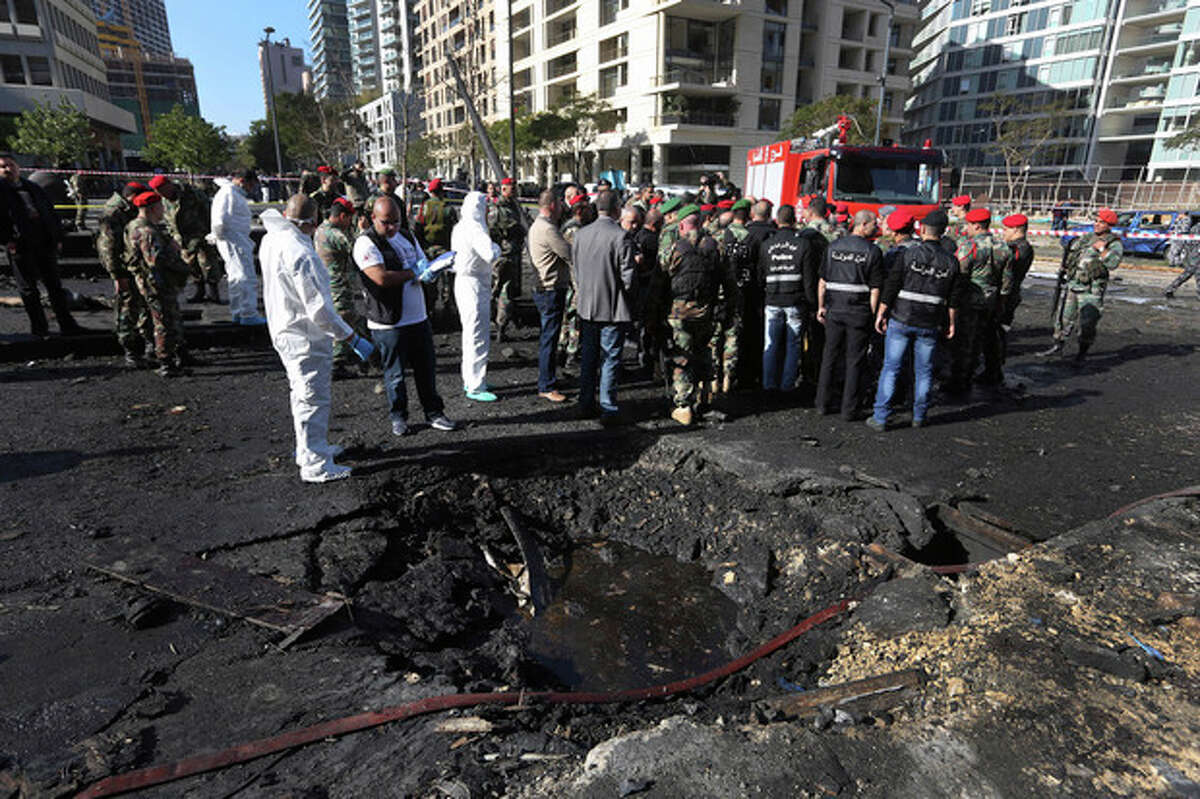 Lebanese army investigators in white coveralls stand next to a blast crater at the scene of an explosion in Beirut, Lebanon, Friday, Dec. 27, 2013. A powerful car bomb tore through a business district in the center of the Lebanese capital Friday, killing Mohammed Chatah, a prominent pro-Western politician and at least five other people in an assassination certain to hike sectarian tensions already soaring because of the civil war in neighboring Syria. (AP Photo/Bilal Hussein)
