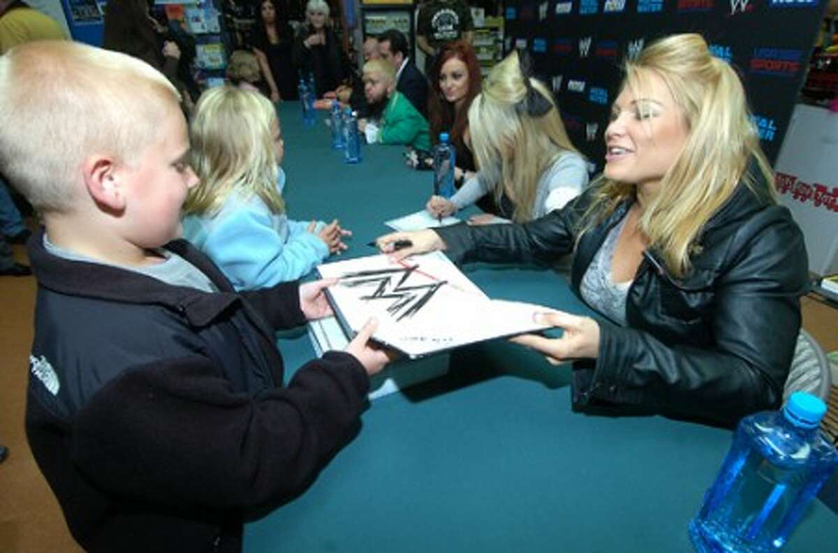 Photo/Alex von Kleydorff. 8 yr old Kevin Brugger from Trumbull gets a WWE book signed by Beth Phoenix after dropping a toy in the bin for Toys for Tots at Tommy k''s in Stamford