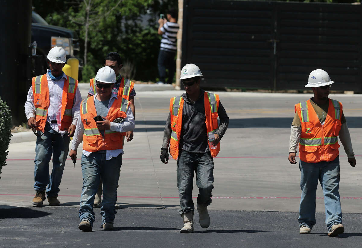 Construction workers leave the scene where San Antonio police investigate Thursday June 16, 2016 on the Loop 1604 access road between Braun and Bandera where a white Honda crashed into a construction zone hurting at least two workers. The extent of the victims injuries is not immediately known, but police said they were both taken to University Hospital.