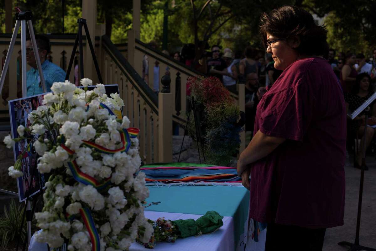 Carol Aguero, 44, of San Antonio quietly studies a memorial with photographs and flowers before the start of a vigil to honor the lives of the 49 victims killed in the recent mass shooting in Orlando, Fl., at Crockett Park in downtown San Antonio, on Thursday, June 16, 2016.