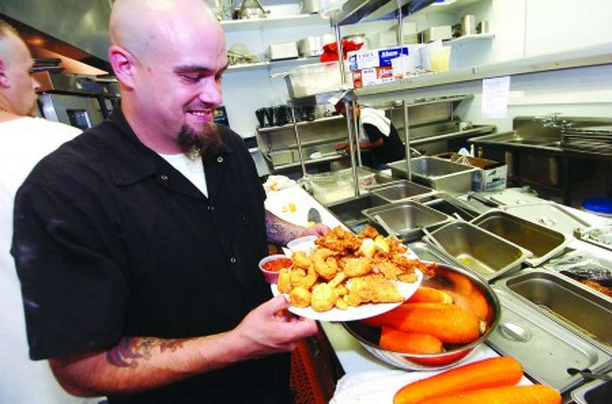 Photo/Alex von Kleydorff. Chris Morgan one of the Head Chefs at Savin Rock Roasting Co. plates up a Clam strip combo that includes scrod. scallops, shrimp and of course clams, served over a bed of french fries