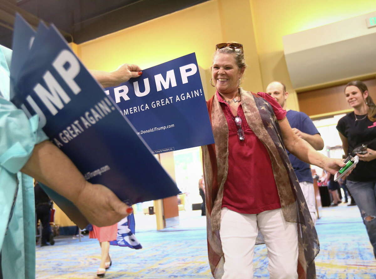 Kimi Clepper, a Donald Trump supporter from Tomball, grabs a sign as she enters a campaign rally at the Woodlands Waterway Marriott, Friday, June 17, 2016, in The Woodlands.