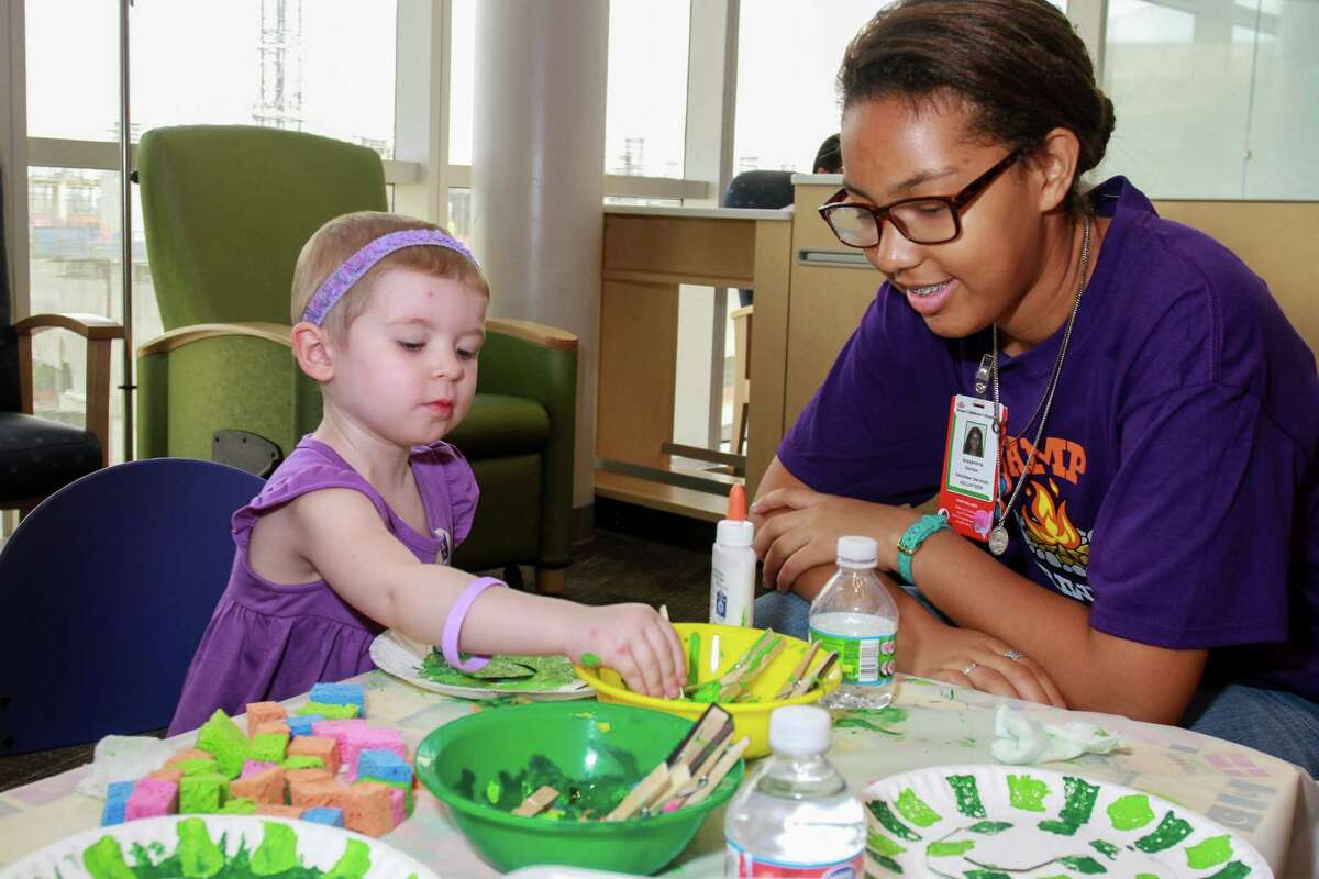 Caitlin Czagas, 2, volunteer Alexandria Gordon doing Snake Painting at Camp Periwinkle Days. Camp Periwinkle Days transforms the Texas Children's Cancer and Hematology Centers waiting rooms into a two-day camp with games, prizes and activities.