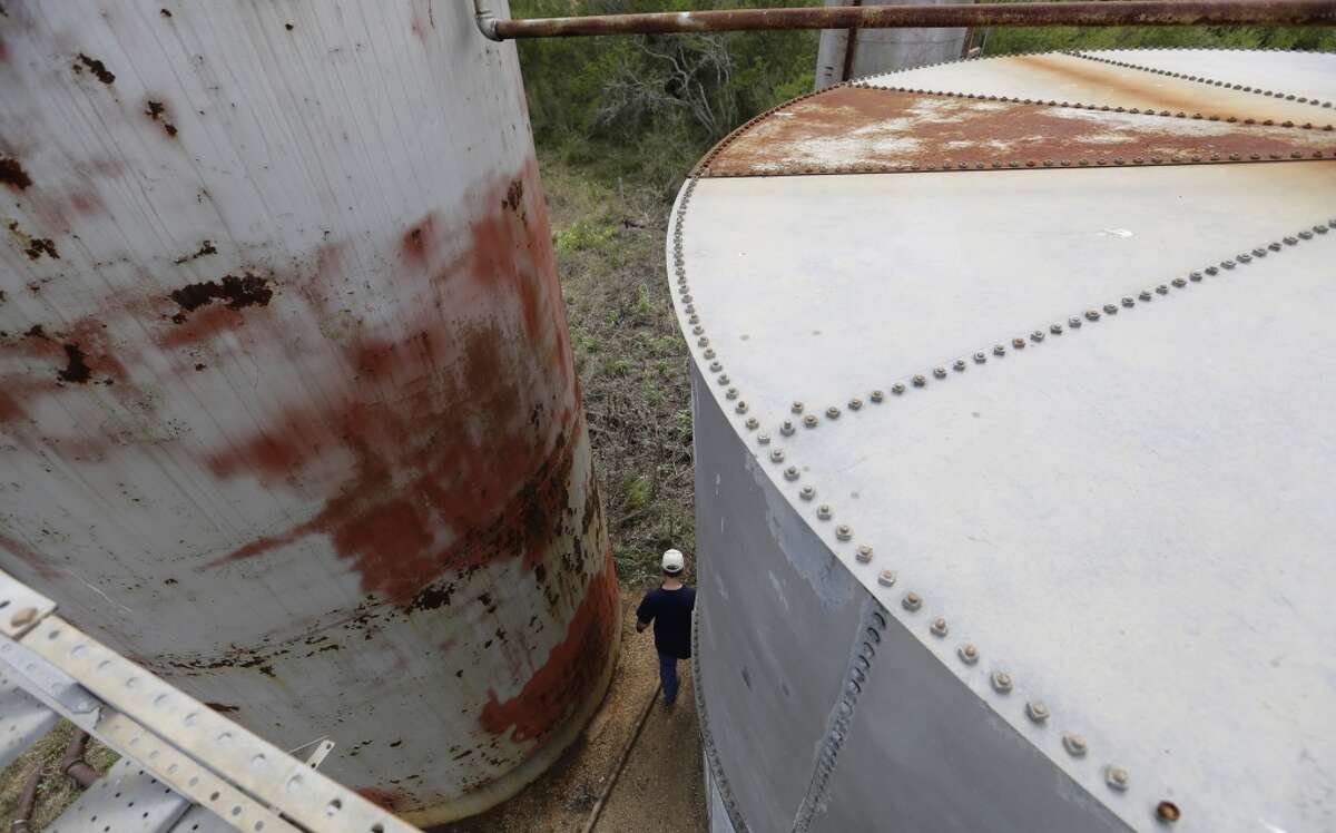 A man walks past old storage tanks near Bigfoot. (AP Photo/Eric Gay)