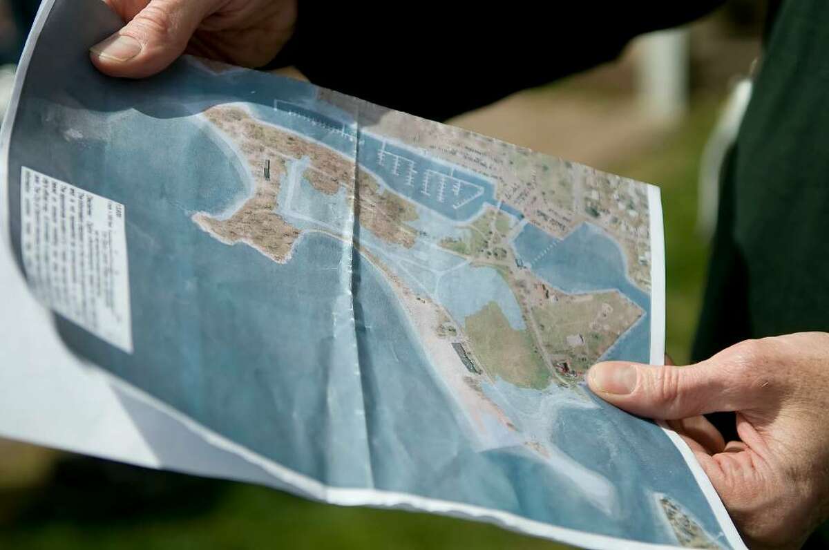 People gather in Cove Island Park on Saturday, April 24, 2010 to create a human tide line. The line shows where the water level would reach if climate change causes sea level to rise 1 meter. Participants consult a map of Cove Island Park. The map had been used to mark off where the human tide line should form. / Shelley Cryan