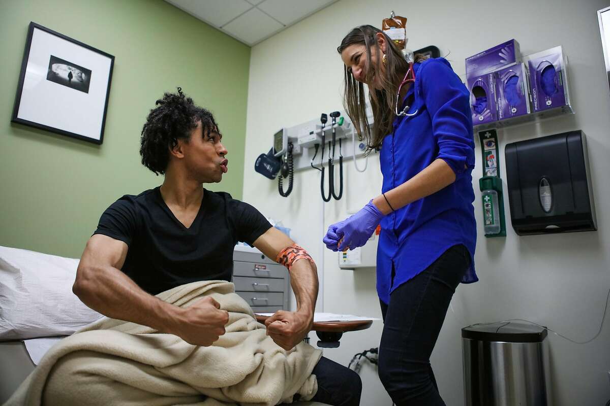 Patient Brandon Kazen-Maddox (left) flexes his muscles when asked how he felt, after after receiving an infusion from Dr. Aliza Norwood (right) as part of a HIV clinical trial, in San Francisco, California, on Thursday, June 16, 2016.