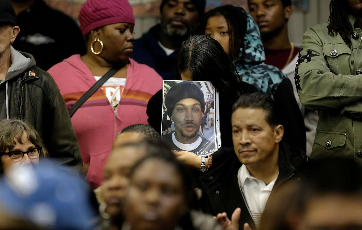 A woman holds a photo of Mario Woods as the San Francisco Police department hosts a town hall meeting in 2015 to discuss the officer-involved shooting in the Bayview neighborhood.