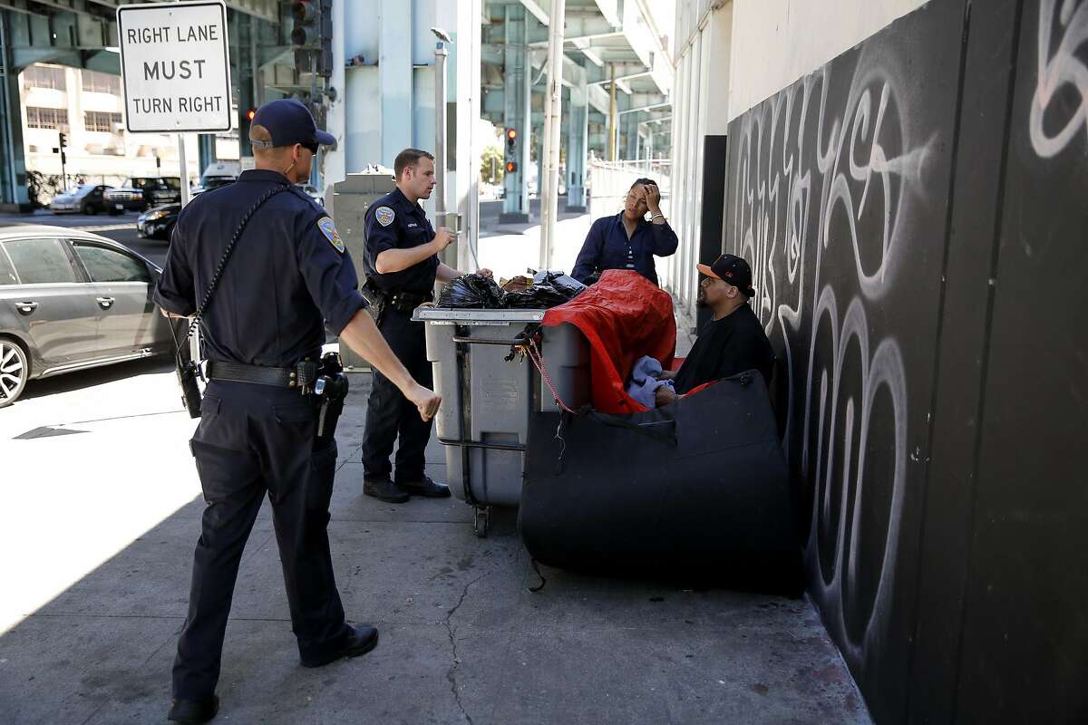 San Francisco Police officers Suhrke (left) and Gerrans tell Mele (center) and Junior, a homeless couple, to move their encampment from the sidewalk near Division and Bryant streets in San Francisco, California, on Wednesday, Aug. 12, 2015.