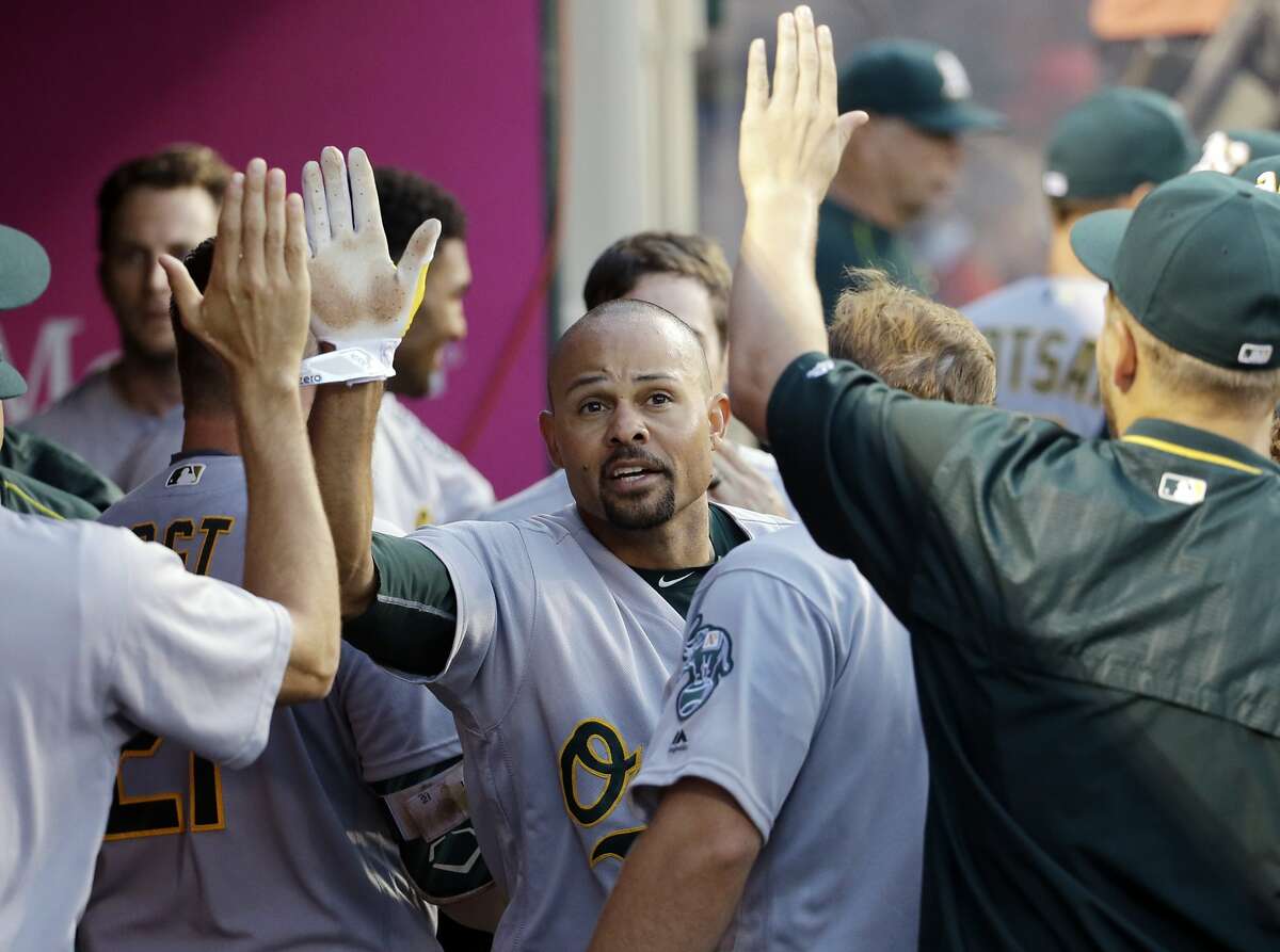 Oakland Athletics' Coco Crisp, center, is greeted by teammates after scoring off a sacrifice fly by Stephen Vogt during the third inning of a baseball game against the Los Angeles Angels Saturday, June 25, 2016, in Anaheim, Calif. (AP Photo/Gregory Bull)