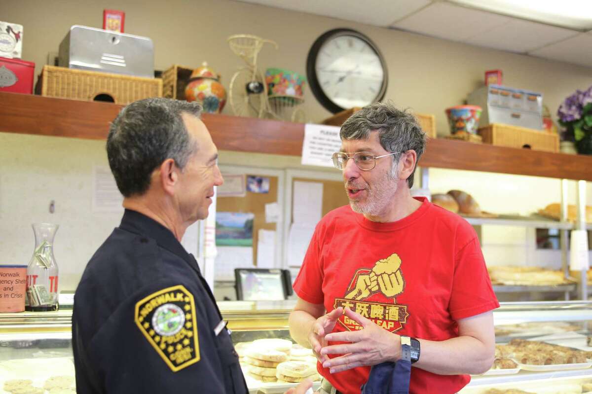 Andy Pearce talks to Officer Cesar Ramirez about unsolicited phone calls during the inaugural Norwalk Police Department's "Coffee with a Cop" opportunity to join police officers for coffee and conversation Tuesday at Muro's Italian Bakery.