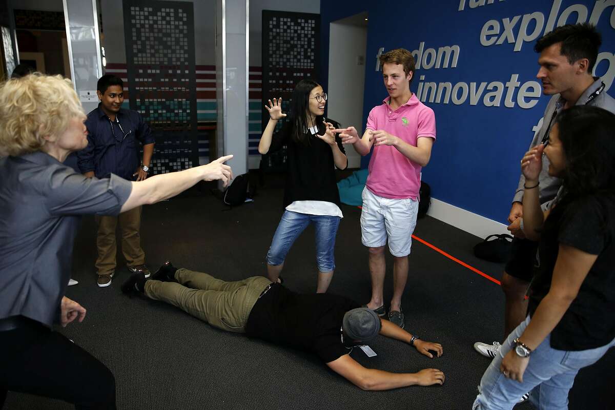 Instructor Diane Rachel (left) directs as Ajmal Jackson (center) lies on the ground pretending to be a boat and other students create a scene around him during an improv class at Draper University in San Mateo, California, on Monday, June 27, 2016.