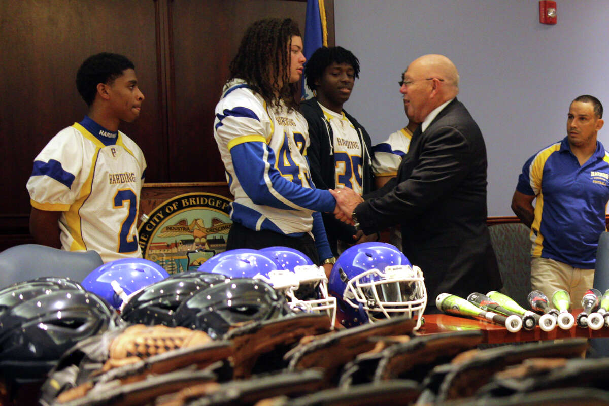 Harding High School football players shake hands with Police Chief A.J. Perez at a press conference announcing a $21,000 grant for sports equipment to be distributed across the city's schools.