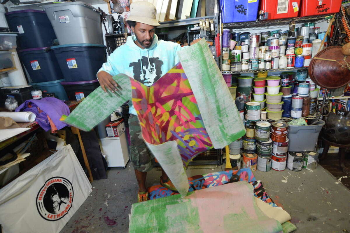 Visual artist Jahmane West tears some hand-painted canvas for use in his graffiti textiles at his studio at Firing Circuits Studios in Norwalk.