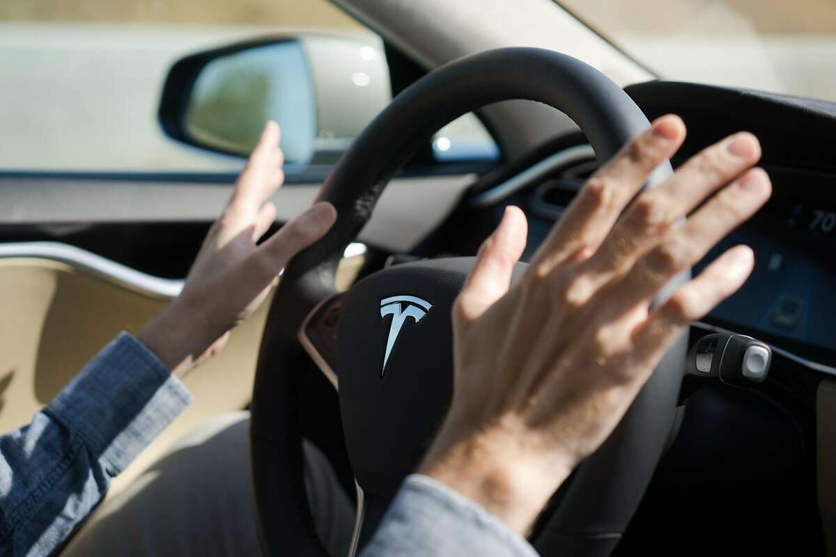Reporter David Baker takes his hands off the steering wheel as the Tesla drives in autopilot in Palo Alto, Calif. on Wednesday, Oct. 14, 2015. An update to Tesla's Autopilot system will aide drivers in changing lanes, parking and steering.