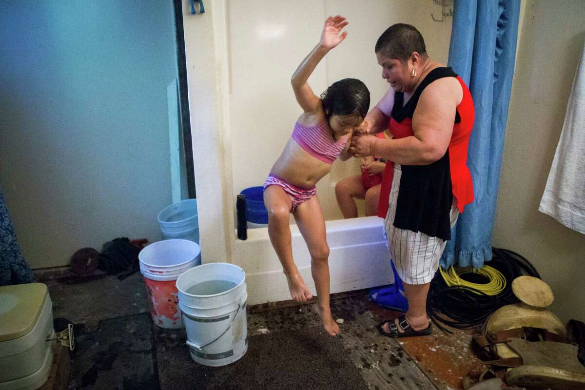 Alyna Garcia, 5, leaps out of the tup after getting bathed with the help of her grandmother Reyna Sanchez, Thursday, June 30, 2016, in New Caney. Sanchez bathes her granddaughters from buckets of water warmed up outside her home by sunlight. Sanchez has been living with her husband Jose Santos Perez in New King's Colony subdivision in Montgomery County for the past five years. Sanchez and Perez are part of a group residents that have filed a lawsuit against the Property Owners Association (POA) and it's president, John Harris.