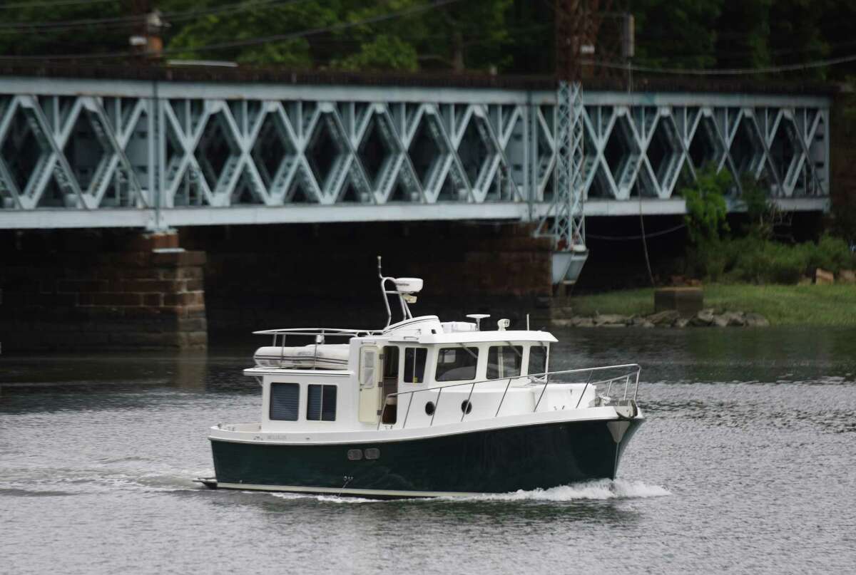 Above, aboat leaves the Cos Cob Harbor near Cos Cob Park in Greenwich. Below, Greenwich Water Club employees Fidel Veltran, left, and Oscar Mejia clean a boat docked in the Cos Cob Harbor. Connecticut has lost more than 10 percent of its commercial and recreational fleet over the past 10 years.