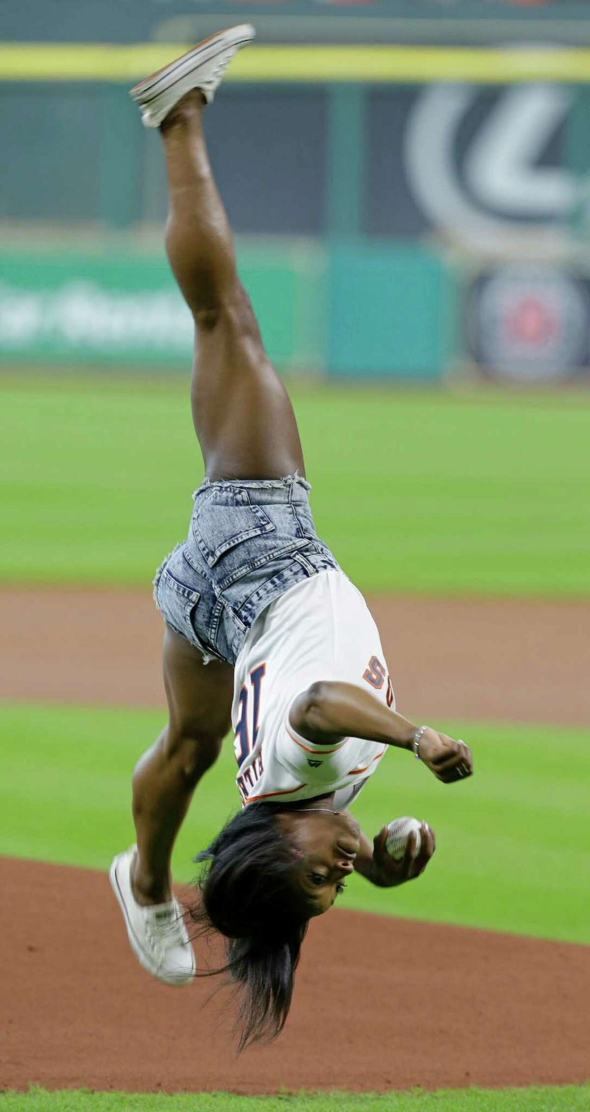 Simone Biles, of Spring, who will participate in the upcoming Olympic Games in Rio, performs a side aerial as she throws out a ceremonial first pitch before the Houston Astros and Seattle Mariners game at Minute Maid Park Monday, July 4, 2016, in Houston.