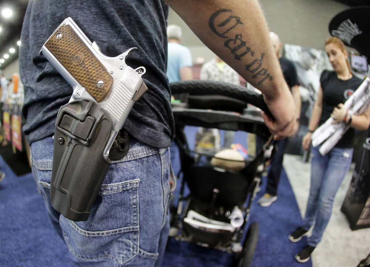 Donald Carder wears his handgun in a holster as he pushes his son, Waylon, in a stroller at the National Rifle Association convention Saturday, May 21, 2016, in Louisville, Ky. Attendees at the convention are permitted to carry firearms under Kentucky's open carry law. (AP Photo/Mark Humphrey)