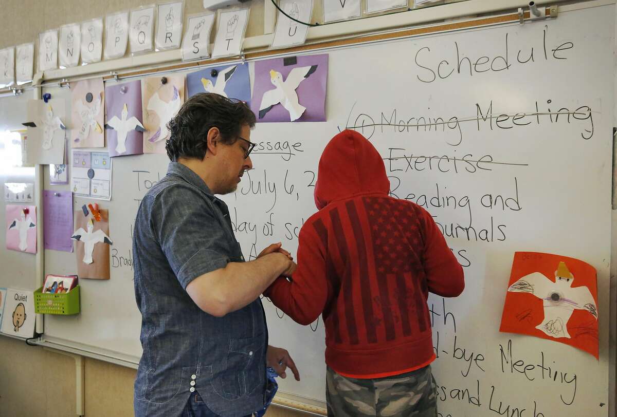 Special Education teacher George Keller helps a student balance as he writes on the white board during the last class of the extended school year for special education students at Sunset Elementary School July 6, 2016 in San Francisco, Calif.