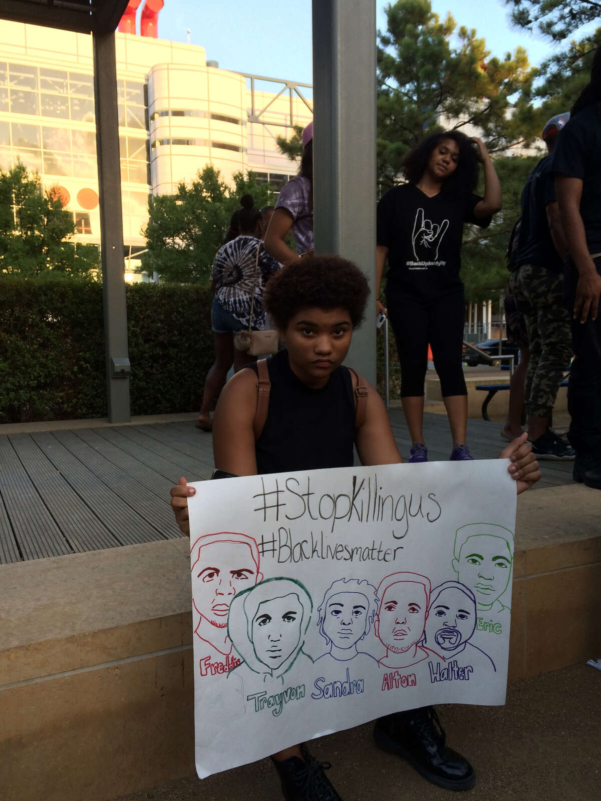 At the Discovery Green event, Angelica McGinnis, 17, shows a sign she drew that includes figures central to the Black Lives Matter movement protesting police shootings of minorities. Of the gathering, she said, "I feel like this is a good start."