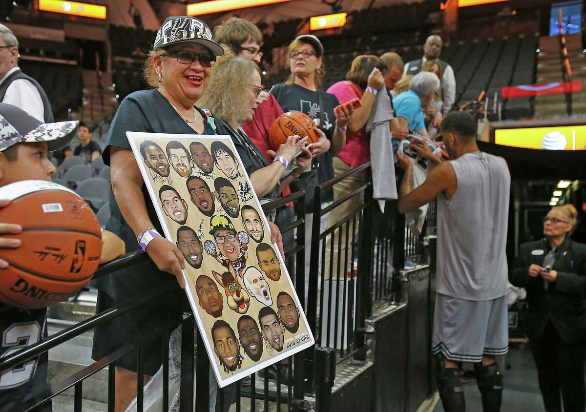 Spurs fan Sovia Laureano (second from left) holds a poster in which she hopes to have players sign as Tim Duncan signs autographs for fans before the game against the Miami Heat at the AT&T Center on March 23, 2016. He was voted the best Spur in the Express-News’ Readers’ Choice.