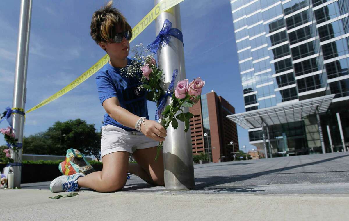 Noelle Hendrix places flowers near the scene of a shooting in downtown Dallas, Friday, July 8, 2016. Snipers opened fire on police officers in the heart of Dallas during protests over two recent fatal police shootings of black men.
