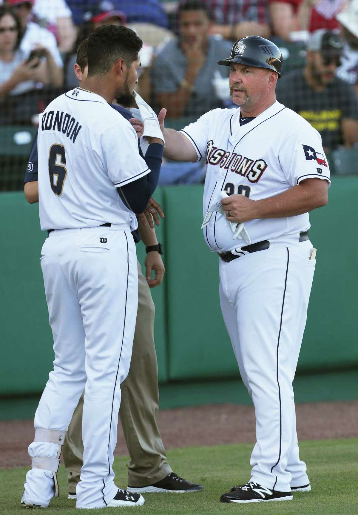Missions manager Phillip Wellman helps an injured Jose Rondon remove the batter's glove as he coaches his players against the Tulsa Drillers at Wolff Stadium on July 1, 2016.