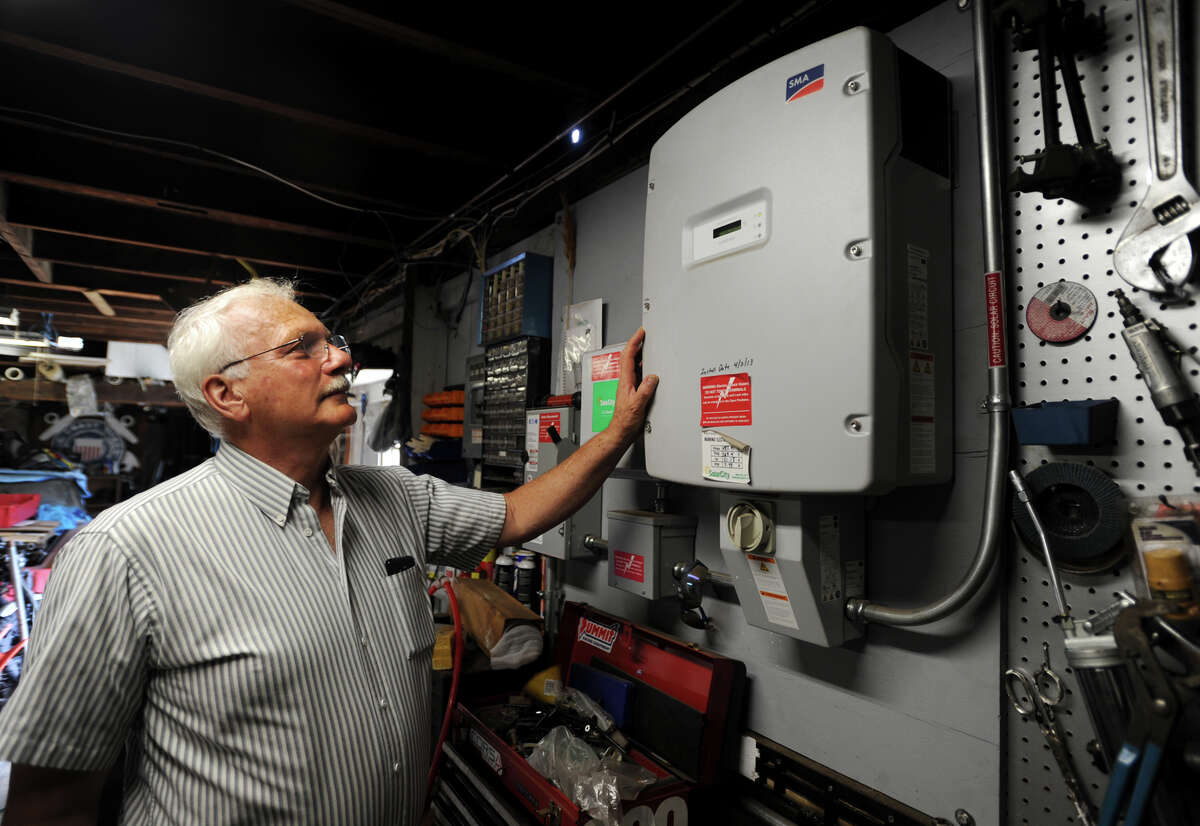 Pieter Moen, a member of Milford’s Energy Advisory Board, shows off his solar power inverter inside the garage of his home on High Street in Milford on Thursday.