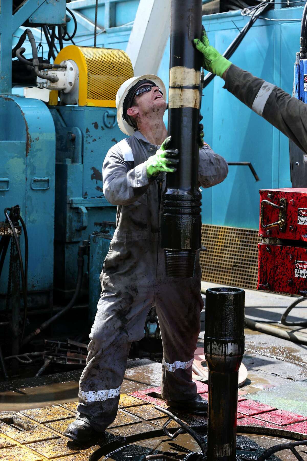 Floor hands guide drilling pipe on an oil drilling rig in the Eagle Ford Shale, where Pioneer Natural Resources has divested some of its holdings.