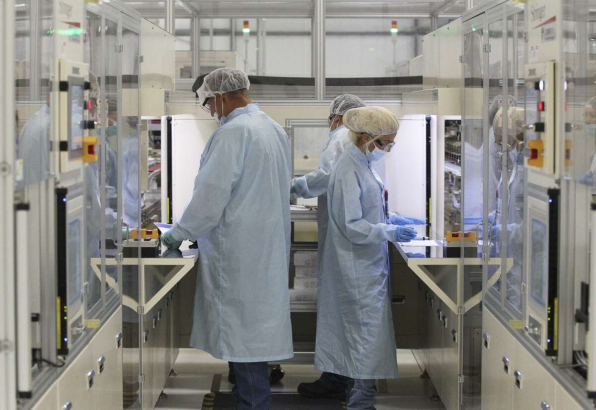File photo of Mission Solar employees in a testing area at its Brooks City Base location. Mission Solar is laying off 170 more workers, after cutting 87 jobs in October.