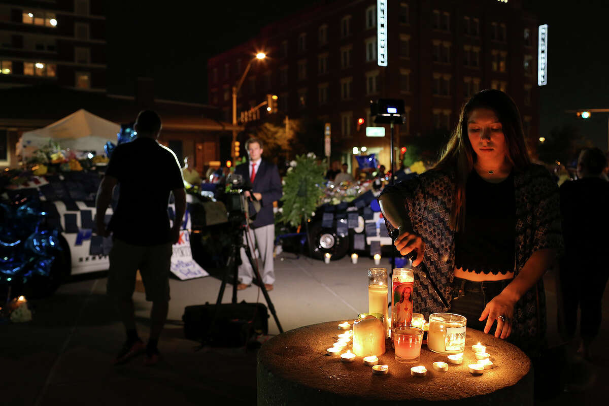 Shelby Garcia, 16, of Midlothian, lights candles at the memorial to the slain and injured officers outside Dallas Police Department Headquarters on Friday, July 8, 2016.