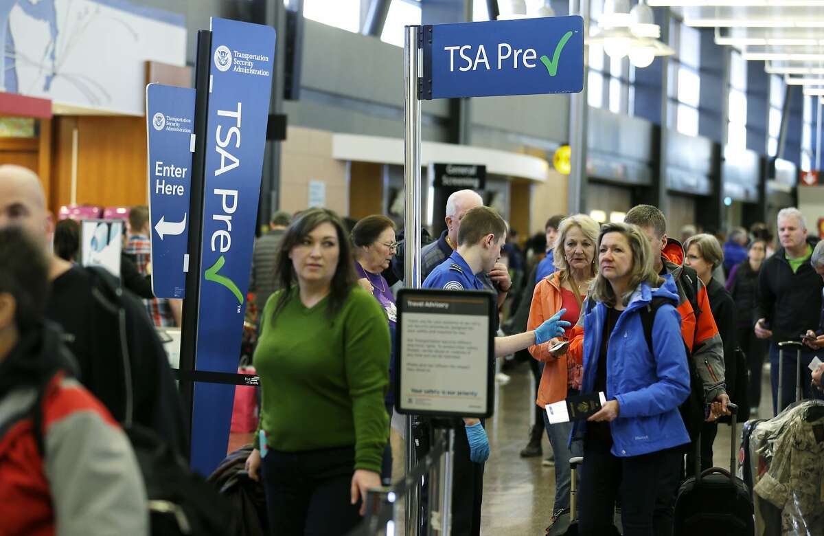 FILE - In this March 17, 2016, file photo, travelers authorized to use the Transportation Security Administration's PreCheck expedited security line at Seattle-Tacoma International Airport in Seattle have their documents checked by TSA workers. Thousands of fliers enrolled in trusted traveler programs such as PreCheck aren�t getting the expedited screening they paid for because of clerical errors with their reservations. (AP Photo/Ted S. Warren, File)