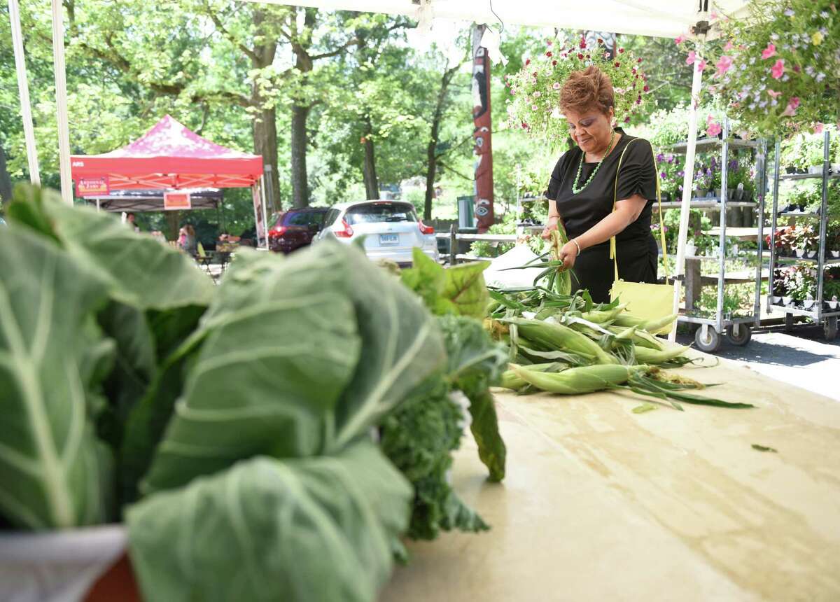 Stamford resident Barbara Brown shucks corn at the Connecticut Grown stand at the Stamford Museum & Nature Center's Farmers' Market in Stamford, Conn. Sunday, July 10, 2016. The market features a variety of local vendors, ranging from produce to soap, and runs every Sunday from 10 a.m. to 2 p.m. through October 9.