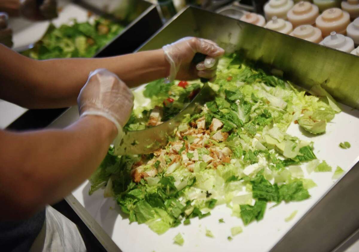 An employee chops a salad at the Chop't Salad location in the Riverside Commons shopping center.