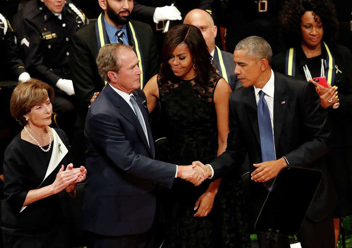 President Barack Obama and former President George W. Bush shake hands as first lady Michelle Obama, and Laura Bush, left, stand by after Bush spoke during a memorial service at the Morton H. Meyerson Symphony Center in Dallas, Tuesday, July 12,2016, for the fallen police officers. Five police officers were killed and several injured during a shooting in downtown Dallas last Thursday night.