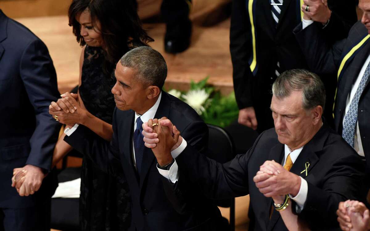 President Barack Obama holds hands with Dallas Mayor Mike Rawlings, right, and first lady Michelle Obama during an interfaith memorial service for the fallen police officers and members of the Dallas community at the Morton H. Meyerson Symphony Center in Dallas, Tuesday, July 12, 2016.