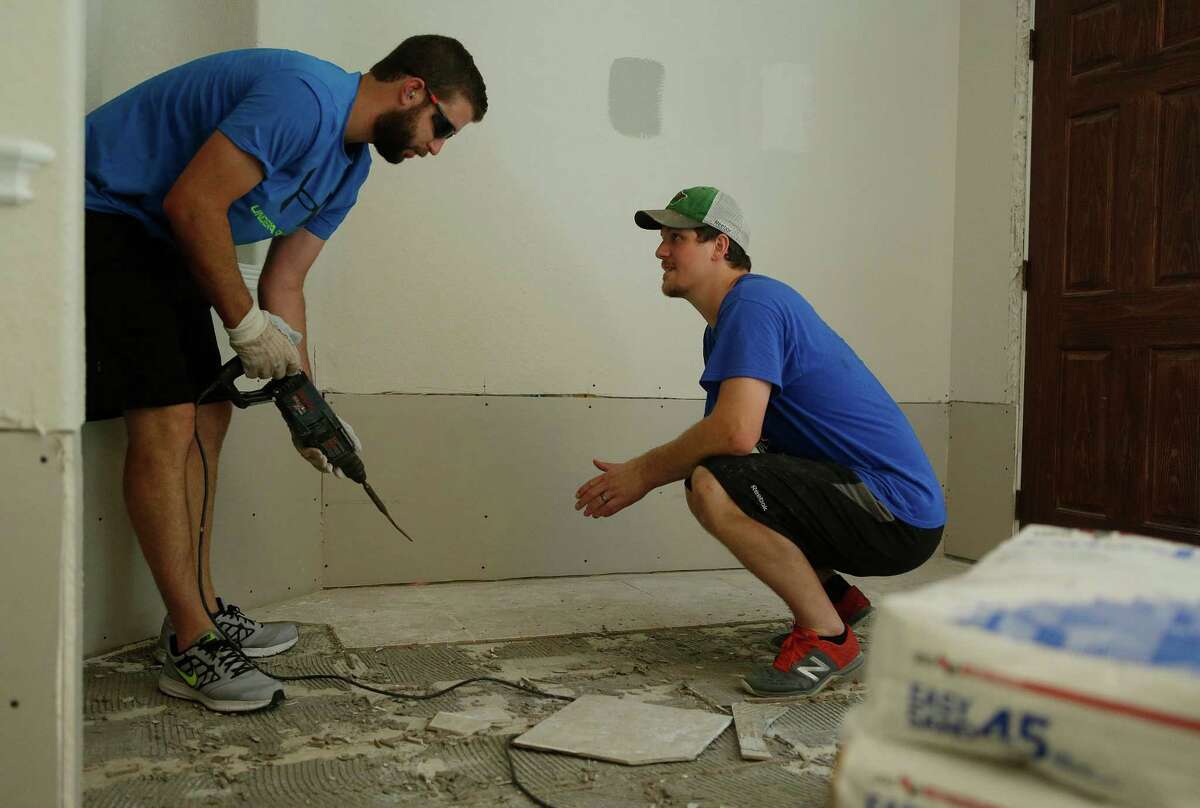 Jarod Palmer (right) gets help from neighbor Zach White removing tile Thursday, June 30, 2016, after recent flooding poured inches of water into their home in Fort Bend County. ( Mark Mulligan / Houston Chronicle )