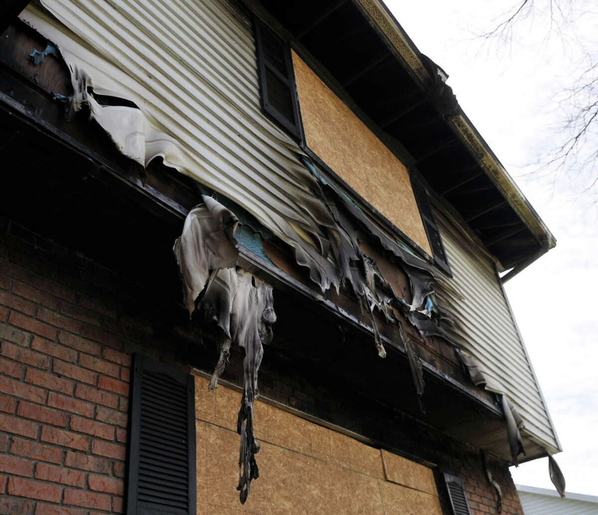 Melted panels hang from the fire damaged Schalren Drive home of Colonie police officer Israel Roman on Friday, April 29, 2016, in Colonie, N.Y. Roman set his house on fire and shot his wife, son and himself. Neighbors complain about the eyesore and fire debris, but town officials said it could be years before the property gets cleaned up because Roman had no will and there are uncertainties about the insurance. (Brittany Gregory / Special to the Times Union)