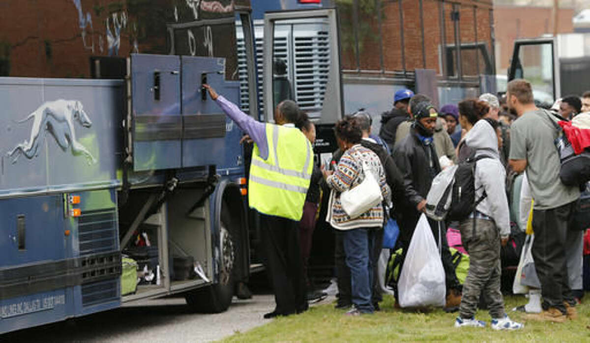 Stranded passengers wait to board buses at a bus maintenance facility near the main bus station where a shooting took place Thursday, March 31, 2016, in Richmond, Va. Virginia State Police say one trooper responding to a shooting at a Richmond bus station and two civilians have been taken to a hospital. A police spokeswoman says the shooting suspect is dead. (AP Photo/Steve Helber)
