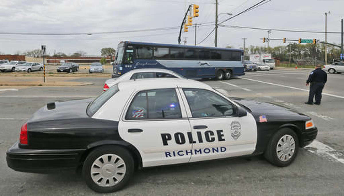 A Greyhound bus passes a police cruiser as it heads to the terminal Thursday, March 31, 2016, in Richmond, Va. Virginia State Police said at least two troopers responding to a shooting at the Richmond bus station and a civilian have been taken to a hospital. A police spokeswoman says the shooting suspect was in custody. (AP Photo/Steve Helber)