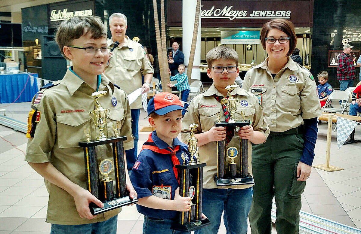 From left, third-place finisher Tyler McKenzie, second-place finisher Caleb Harvey and first-place finisher Carter Fox pose with Heartland District unit service director Abby Scherze.