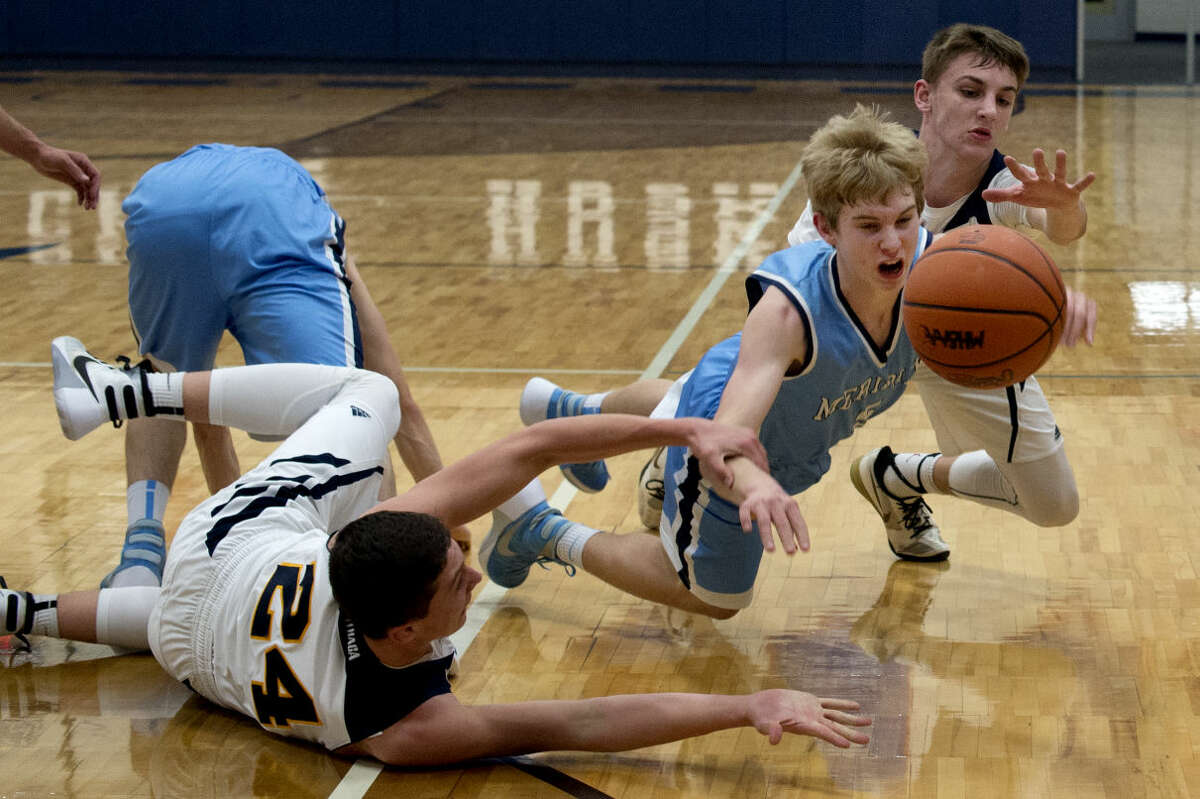 Meridian's Garrett Stockford, center, lunges for a loose ball while Ithaca's Joey Bentley, left, and Spence DeMull fight for possession during Friday's Class C boys' basketball district final at Hemlock High School.