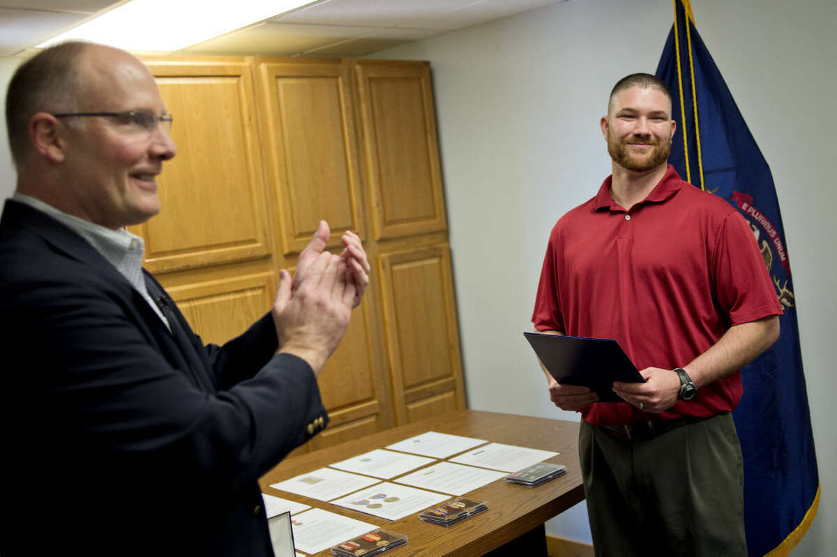 Army veteran Micheal Tacey, of Bay City, right, smiles as U.S. Rep. John Moolenaar and members of Tacey's family clap during a medal presentation ceremony on Monday at Moolenaar's Midland office. Tacey served four-and-a-half years in the U.S. Army, including one tour in Iraq for 14 months.
